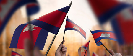 Cambodia flags in their hands on a blurred urban backgroundの写真素材