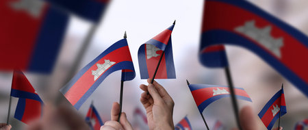 Cambodia flags in their hands on a blurred urban backgroundの写真素材