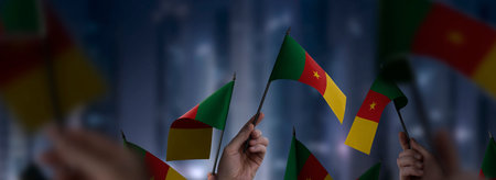 Cameroon flags in their hands on a blurred urban backgroundの写真素材