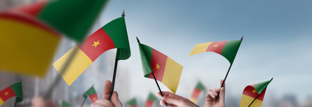 Cameroon flags in their hands on a blurred urban backgroundの写真素材