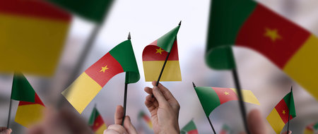 Cameroon flags in their hands on a blurred urban backgroundの写真素材