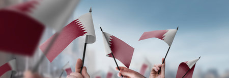 Qatar flags in their hands on a blurred urban backgroundの写真素材