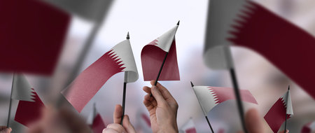 Qatar flags in their hands on a blurred urban backgroundの写真素材