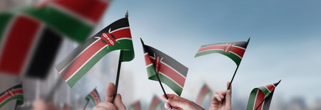 Kenya flags in their hands on a blurred urban backgroundの写真素材