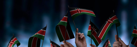 Kenya flags in their hands on a blurred urban backgroundの写真素材