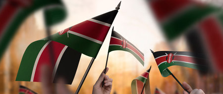 Kenya flags in their hands on a blurred urban backgroundの写真素材