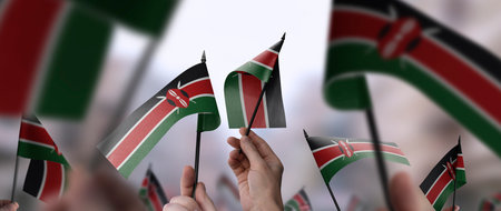 Kenya flags in their hands on a blurred urban backgroundの写真素材