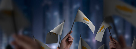 Cyprus flags in their hands on a blurred urban backgroundの写真素材