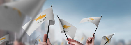 Cyprus flags in their hands on a blurred urban backgroundの写真素材
