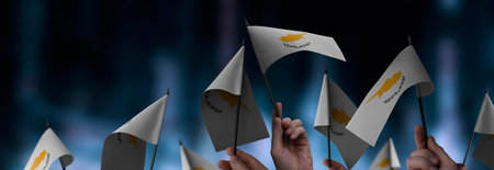 Cyprus flags in their hands on a blurred urban backgroundの写真素材