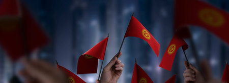 Kirghizia flags in their hands on a blurred urban backgroundの写真素材