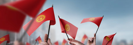 Kirghizia flags in their hands on a blurred urban backgroundの写真素材