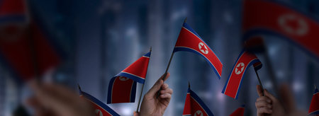 North Korea flags in their hands on a blurred urban backgroundの写真素材