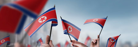 North Korea flags in their hands on a blurred urban backgroundの写真素材