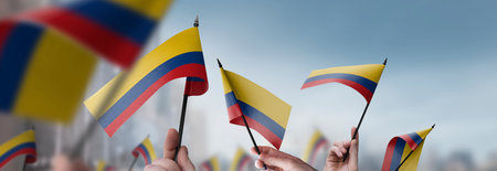 Colombia flags in their hands on a blurred urban backgroundの写真素材