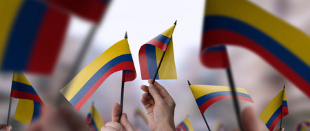 Colombia flags in their hands on a blurred urban backgroundの写真素材