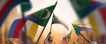 Comoros flags in their hands on a blurred urban backgroundの写真素材