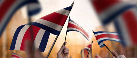 Costa Rica flags in their hands on a blurred urban background