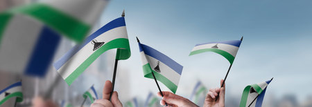 Lesotho flags in their hands on a blurred urban background
