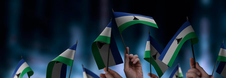 Lesotho flags in their hands on a blurred urban backgroundの写真素材
