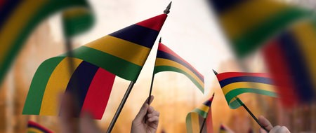 Mauritius flags in their hands on a blurred urban background