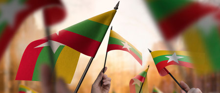 Myanmar flags in their hands on a blurred urban background