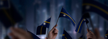 Nauru flags in their hands on a blurred urban background