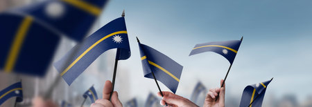Nauru flags in their hands on a blurred urban backgroundの写真素材