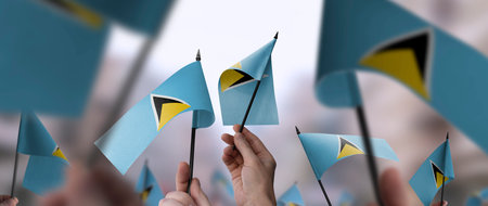 Saint Lucia flags in their hands on a blurred urban backgroundの写真素材