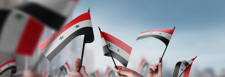 Syria flags in their hands on a blurred urban background