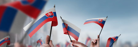 Slovakia flags in their hands on a blurred urban backgroundの写真素材