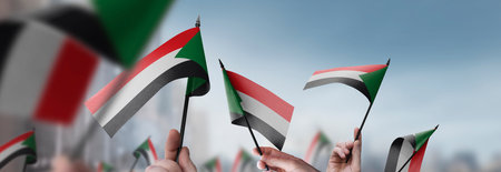 Sudan flags in their hands on a blurred urban backgroundの写真素材