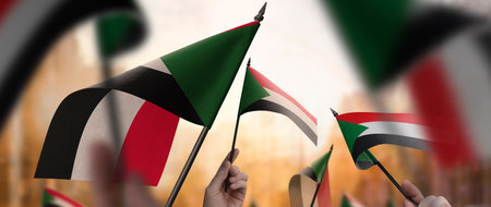 Sudan flags in their hands on a blurred urban backgroundの写真素材