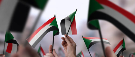 Sudan flags in their hands on a blurred urban backgroundの写真素材