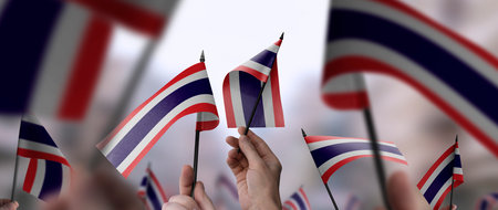 Thailand flags in their hands on a blurred urban background