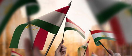 Tajikistan flags in their hands on a blurred urban background