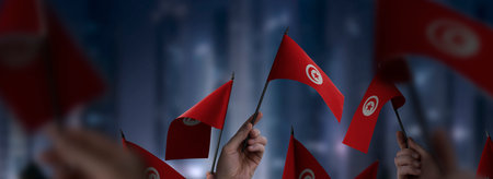 Tunisia flags in their hands on a blurred urban backgroundの写真素材
