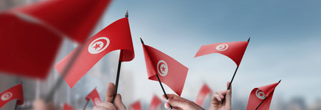 Tunisia flags in their hands on a blurred urban backgroundの写真素材
