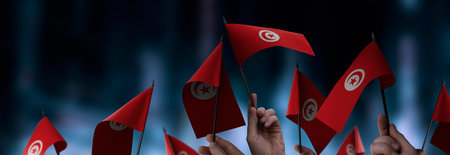 Tunisia flags in their hands on a blurred urban backgroundの写真素材