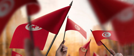 Tunisia flags in their hands on a blurred urban backgroundの写真素材