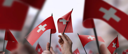 Switzerland flags in their hands on a blurred urban backgroundの写真素材