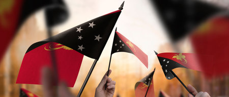 Papua New Guinea flags in their hands on a blurred urban backgroundの写真素材