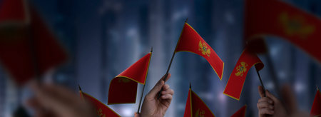 Montenegro flags in their hands on a blurred urban backgroundの写真素材
