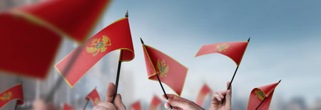 Montenegro flags in their hands on a blurred urban backgroundの写真素材
