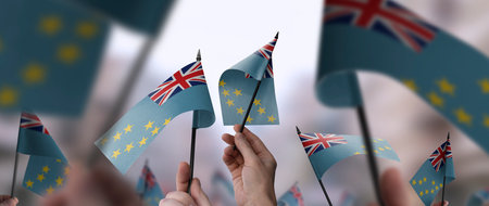 Tuvalu flags in their hands on a blurred urban background
