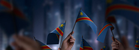 Democratic Republic of the Congo flags in their hands on a blurred urban background