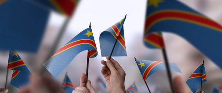 Democratic Republic of the Congo flags in their hands on a blurred urban background