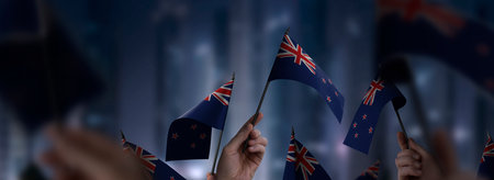 New Zealand flags in their hands on a blurred urban background