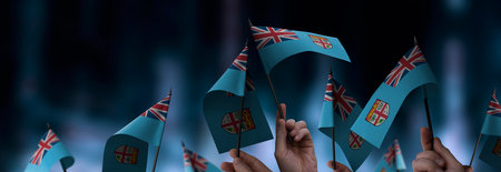 Fiji flags in their hands on a blurred urban backgroundの写真素材