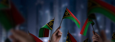 Vanuatu flags in their hands on a blurred urban backgroundの写真素材
